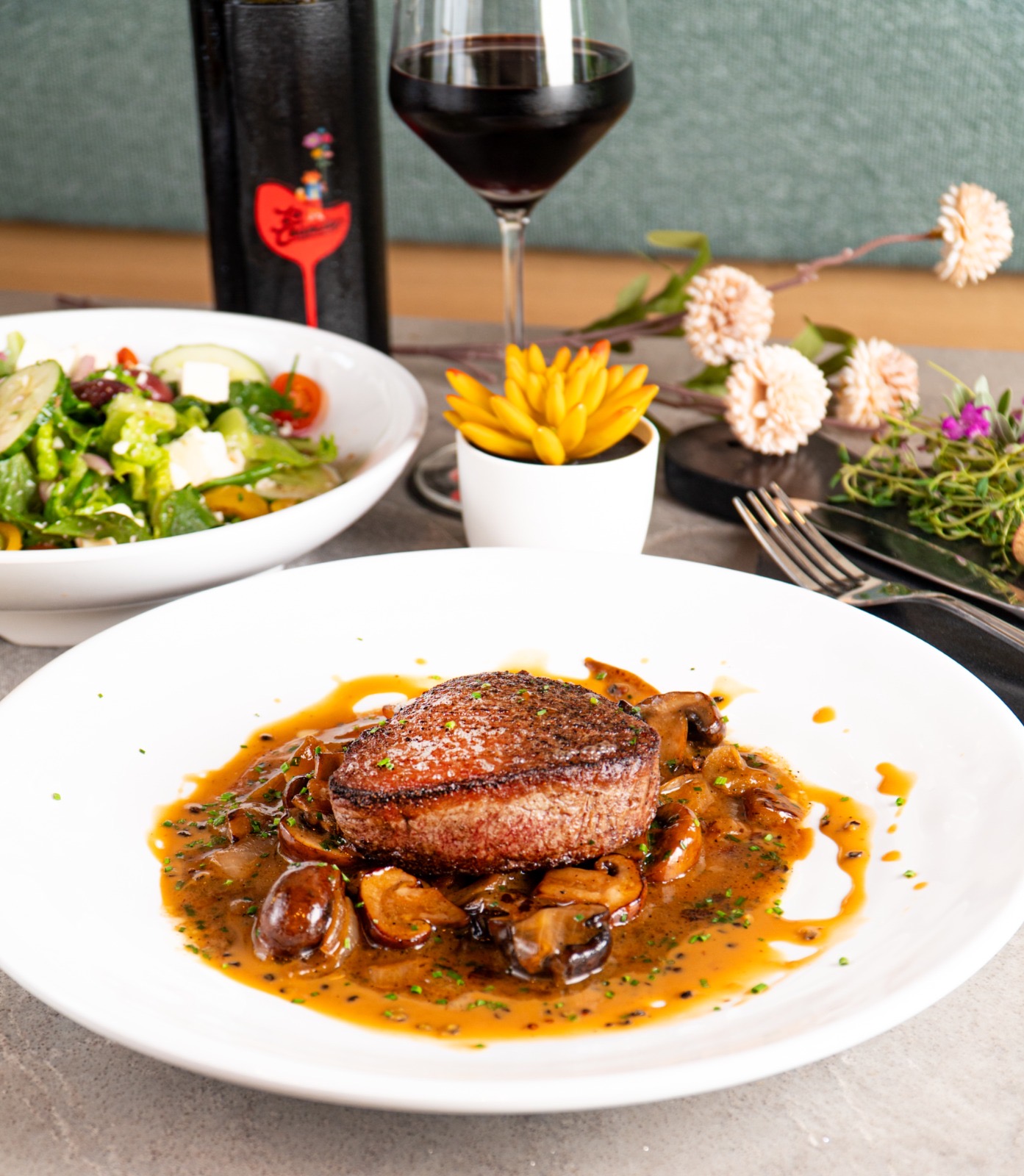 Plated filet with mushroom sauce, side salad and red wine
